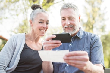 A mature couple deposit a check with a smart phone using eDeposit