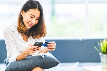A young woman holds her cell phone and credit card