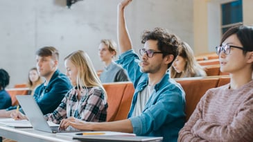 A college student raises his hand in class