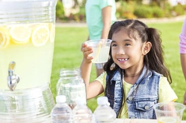 A young girl works a lemonade stand