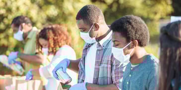 Volunteers packaging canned goods wearing face masks and gloves
