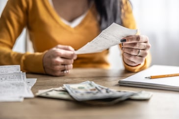 A woman reviewing receipts with cash and paperwork across the table