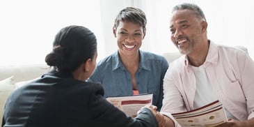 A couple meets with a retirement consultant and they shake hands