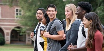 A group of college students walks together on their college campus