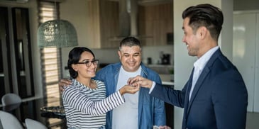 A realtor hands keys to a happy couple who have just purchased a home