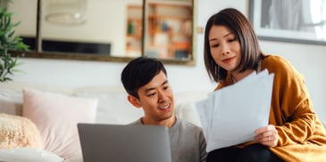 A couple sit in their living room and review their financial statements