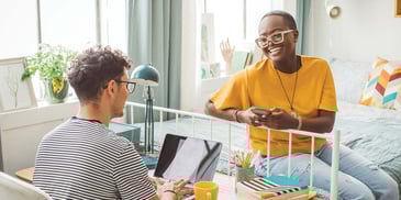 2 smiling college students in a dorm room