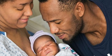 Parents looking admiringly at and holding their newborn baby in the hospital