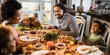 A young family sits around their dining room table for Thanksgiving dinner