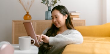 A young woman sitting in her living room using a mobile tablet