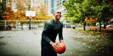 A middle-aged man playing basketball outdoors in a park, about to take a shot