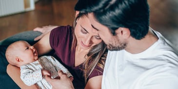 New parents holding their newborn child and smiling