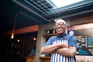 A proud business owner stands in uniform, smiling.
