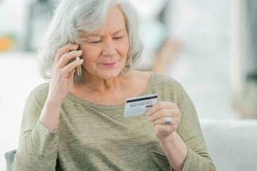 older woman on the phone  holding a credit card