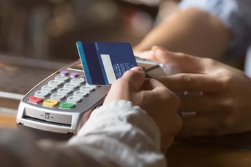 A customer taps their credit card at a POS terminal