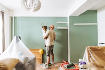 A man and his young child paint a room in their house