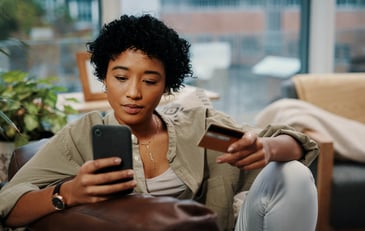 A young woman uses her credit card on her smart phone.