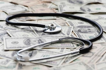 A stethoscope sits atop a pile of cash.