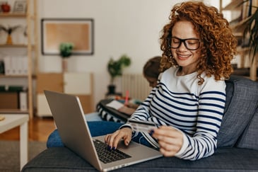 woman holding a credit card with her laptop