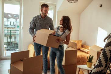 A young man and woman unload boxes into their new living room.