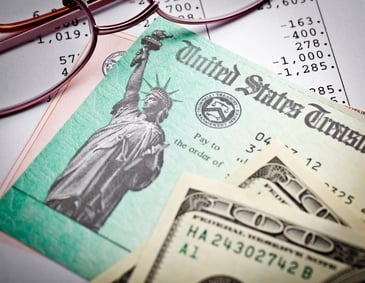A tax return check sits among some cash on a table.