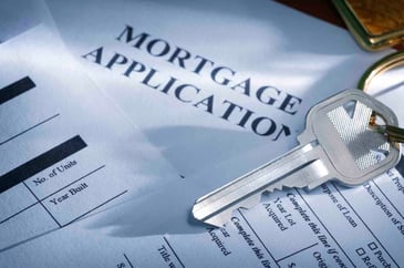 A key sits on top of a mortgage application.