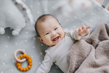 a baby in a crib next to a toy ring