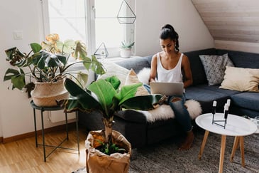 A woman sits in her comfortable living room on her laptop.