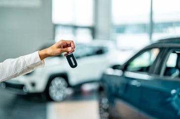 A car dealer hands over the keys in a showroom.