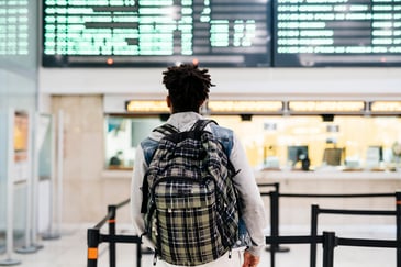 A recent student stands in a train station waiting to board
