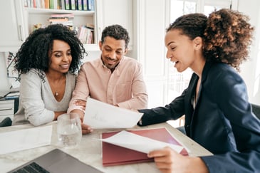 Three people evaluating a financial sheet