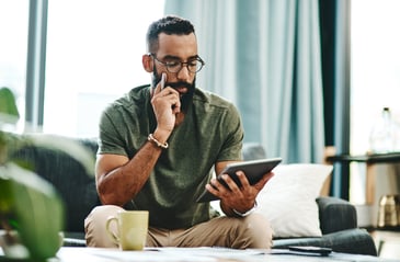 Man sits on a couch with a tablet