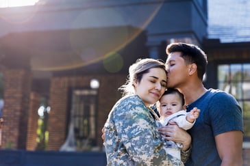 A military family celebrates outside their new home