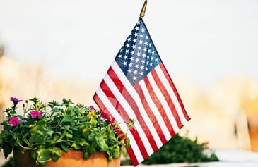 A small American flag placed in a garden planter