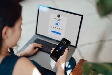 Woman using two-factor authentication on her phone to log into a laptop for added security.