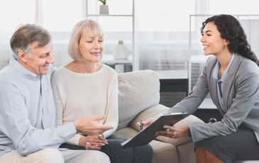 Smiling couple discussing home loan options with a financial advisor in a bright, comfortable office setting.