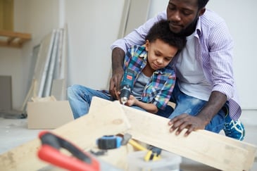 A father works on a DIY home construction project with his young son