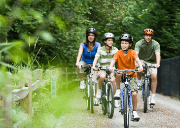 A family rides bikes on a local trail in the spring