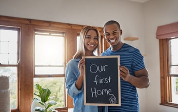 A couple stand in the living room of their first home that they just purchased